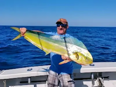 Angler standing with spectacularly colored mahi on his offshore charter trip.